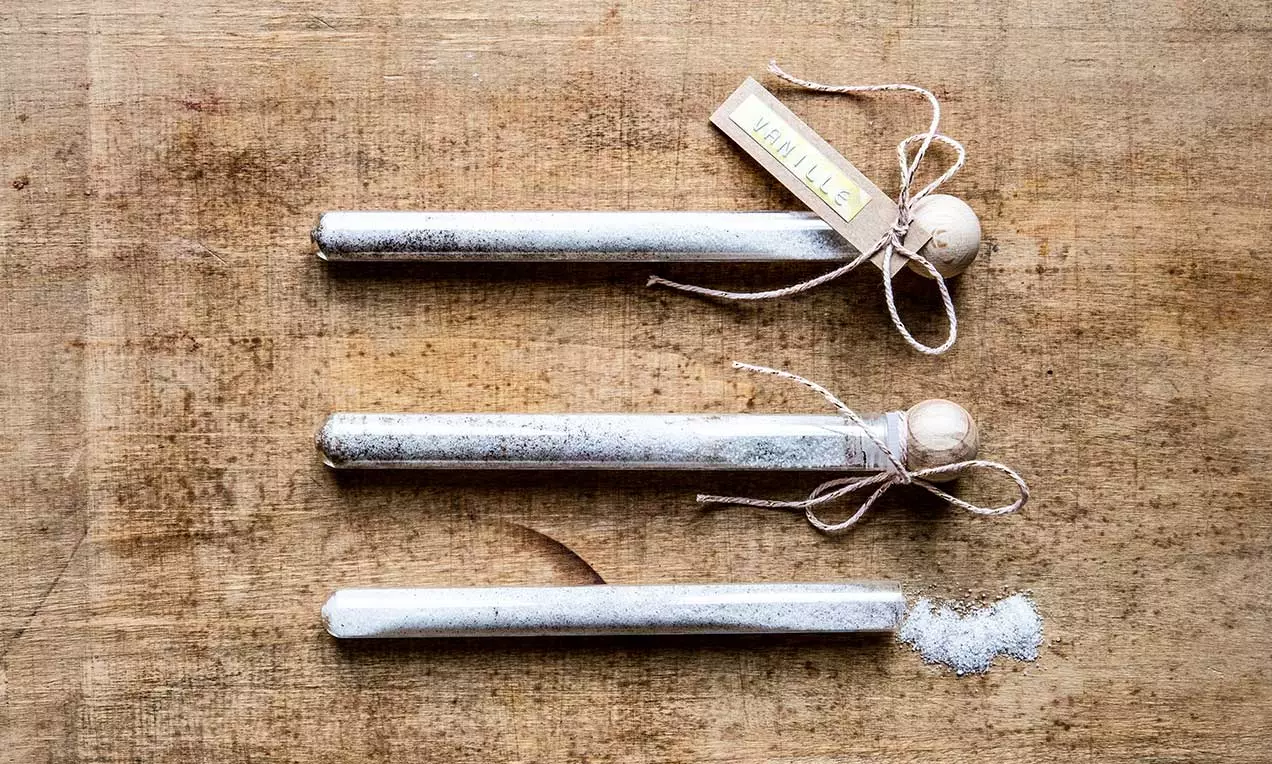 Fines tubes transparents remplis de sel vanillé blanc cristallin, fermés par des bouchons en bois et décorés de ficelles naturelles